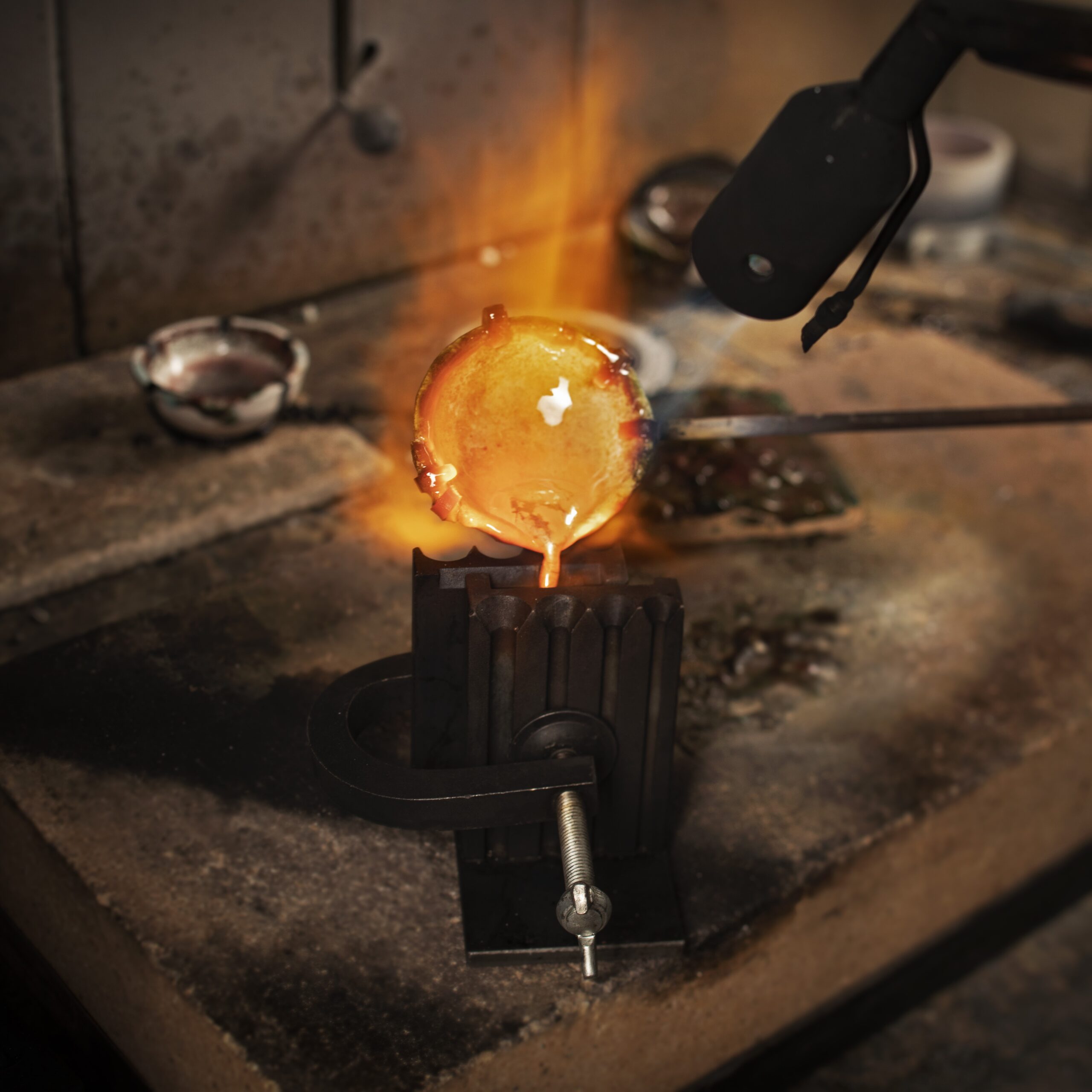 Guldsmed som gjuter metall med en keramisk smältugn och smältugnshållare